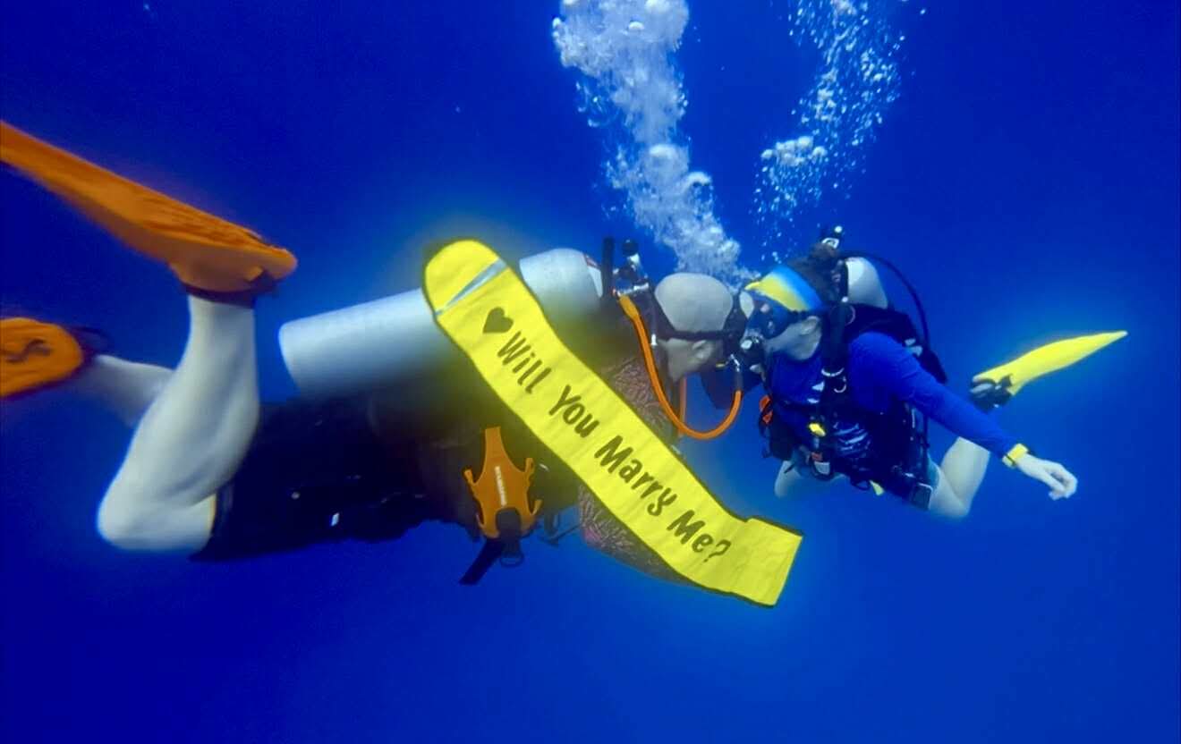 A DSMB with "Will You Marry Me?" written on it and two divers